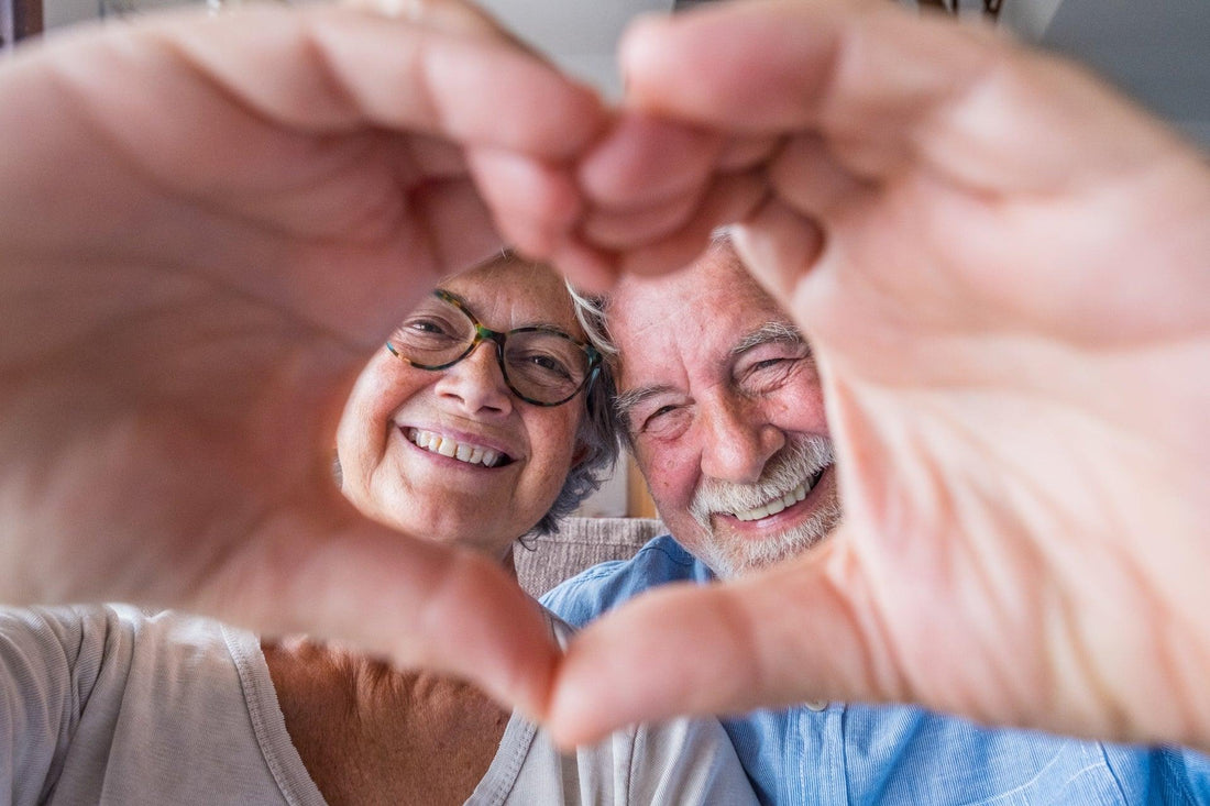 Affectionate older active adult couple making heart with hands