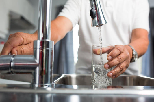 Senior man at sink hydrating for improved health and wellness.