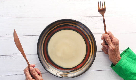 Older woman holding utensils in front of empty plate