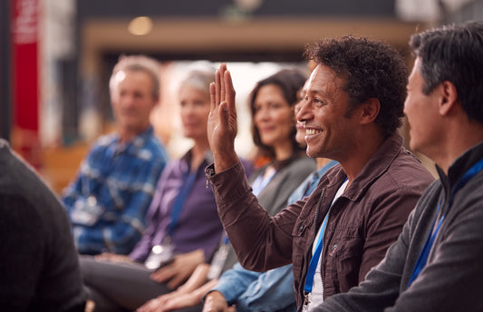 older adult in presentation at hemp expo raising hand