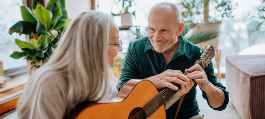 Senior couple playing guitar together in cozy room